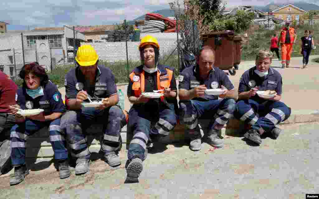 Petugas penyelamatan beristirahat dan makan menyusul gempa di Amatrice, Italia tengah (25/8). (Reuters/Ciro De Luca)