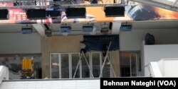 کارگران بنر هفتادویکمین جشنواره کن را بر سردر کاخ جشنواره نصب می‌کنند