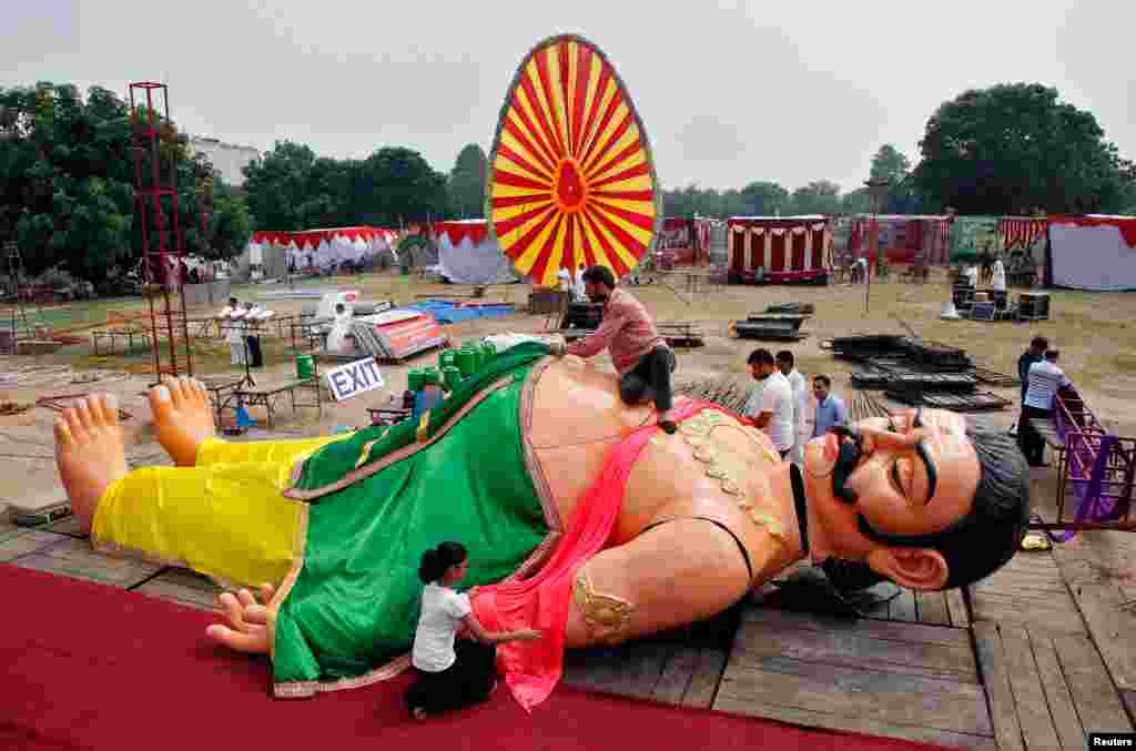 Para pekerja memasang pakaian pada patung Kumbhakarna, saudara termuda Rahwana, untuk acara karnaval di Chandigarh, India.
