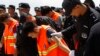 In this photo taken on Oct 12, 2017, Chinese, in an orange vest, arrested over an alleged internet scam, are escorted by Chinese police officers before boarding at Phnom Penh International Airport, in Phnom Penh, Cambodia. 