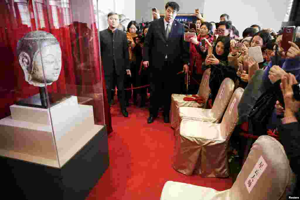 People take pictures of the head of a Buddha statue that is some 1,500-years-old, moments after it was presented at the National Museum of China in Beijing.