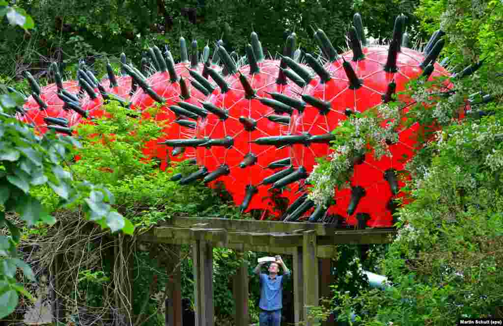 A man takes a picture of the art installation 'Visitors' by artist Andre Tempel, at the Frommannsche Skulpturen garden in Jena, Germany.