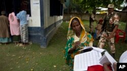 a woman checks her papers as villagers check their names in the final list of National Register of Citizens in Morigaon district, Assam, India, Aug. 31, 2019.