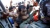 People are held back as crewmen deliver aid in an emergency drop on a U.S. Navy Seahawk helicopter in San Jose, Philippines, Nov. 18, 2013.