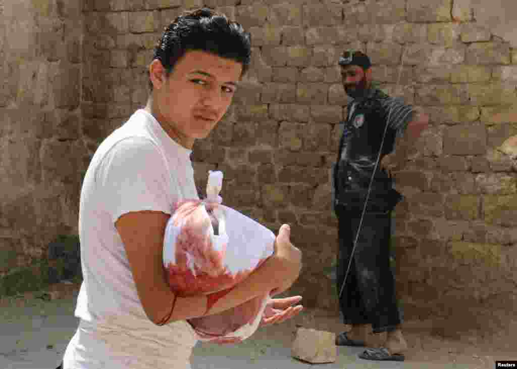 Seorang pria membawa jenazah bayi yang tewas akibat serangan udara di Bab al-Nairab, Aleppo, Suriah.