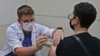 Un agent de santé israélien administre une troisième dose du vaccin Pfizer-BioNtech COVID-19 à un patient, au service de santé Maccabi à Jérusalem le 20 août 2021.