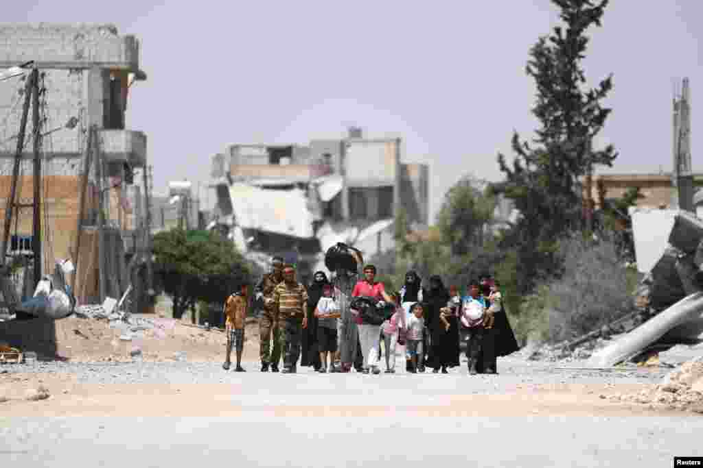 Para pejuang dari Lasykar Demokrasi Suriah (SDF) melindungi warga yang mengungsi dari konflik antara SDF dengan militan ISIS di kota Manbij, Aleppo, Suriah utara.