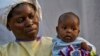 FILE - Two-month-old Lahya Kathembo, whose mother and father died of Ebola, is carried by a nurse waiting for test results at an Ebola treatment center in Beni, DRC, July 17, 2019.