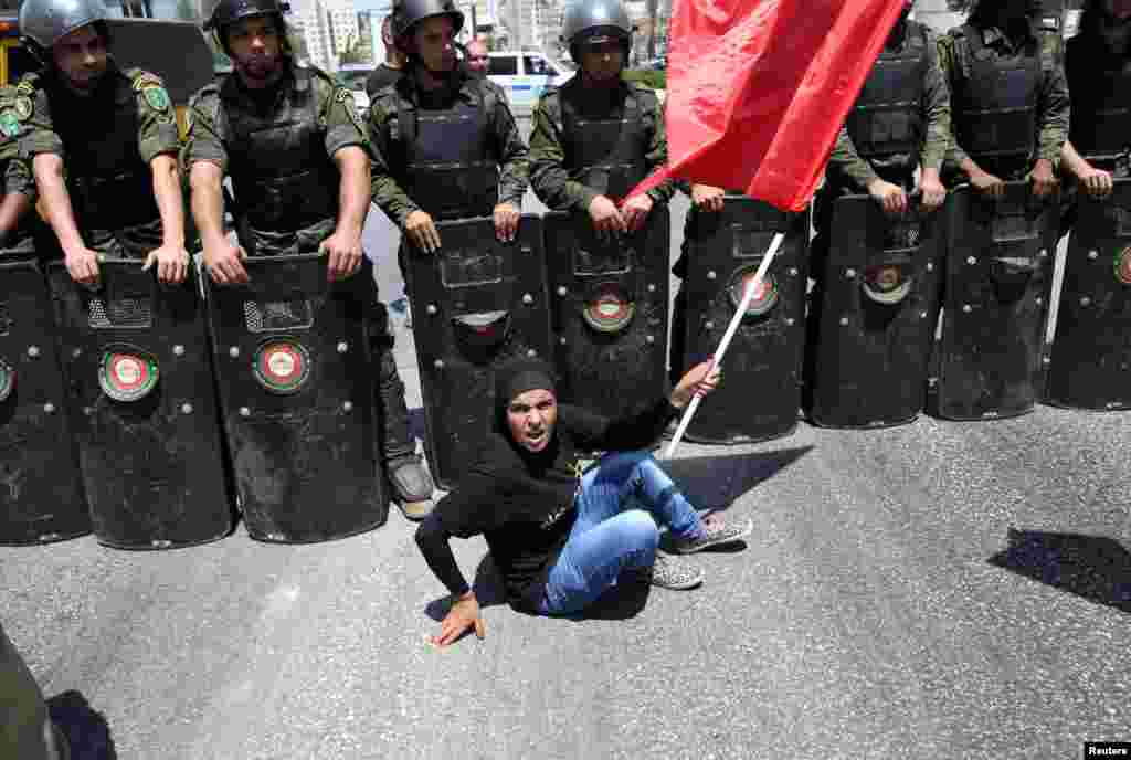 Seorang demonstran perempuan Palestina duduk di depan pasukan keamanan Israel dalam aksi untuk mendukung tahanan Palestina yang melakukan mogok makan di penjara Israel, dalam aksi di Ramallah, Tepi Barat.