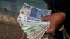 FILE - A vendor holds 'chacho' currency at the Exchange Service Center to convert them to Argentine pesos in La Rioja, Argentina, Sept. 13, 2024. 