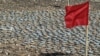 FILE - A red flag is placed by landmines removed by the Libyan army to be destroyed later, during an operation to clear a minefield near Tubruq, Libya, June 7, 2008.