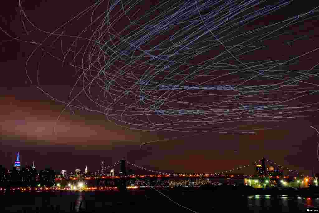 LED lights attached to pigeons leave light trails in the sky while they fly as part of the "Fly By Night" art installation by Duke Riley above the Brooklyn borough of New York, May 5, 2016.