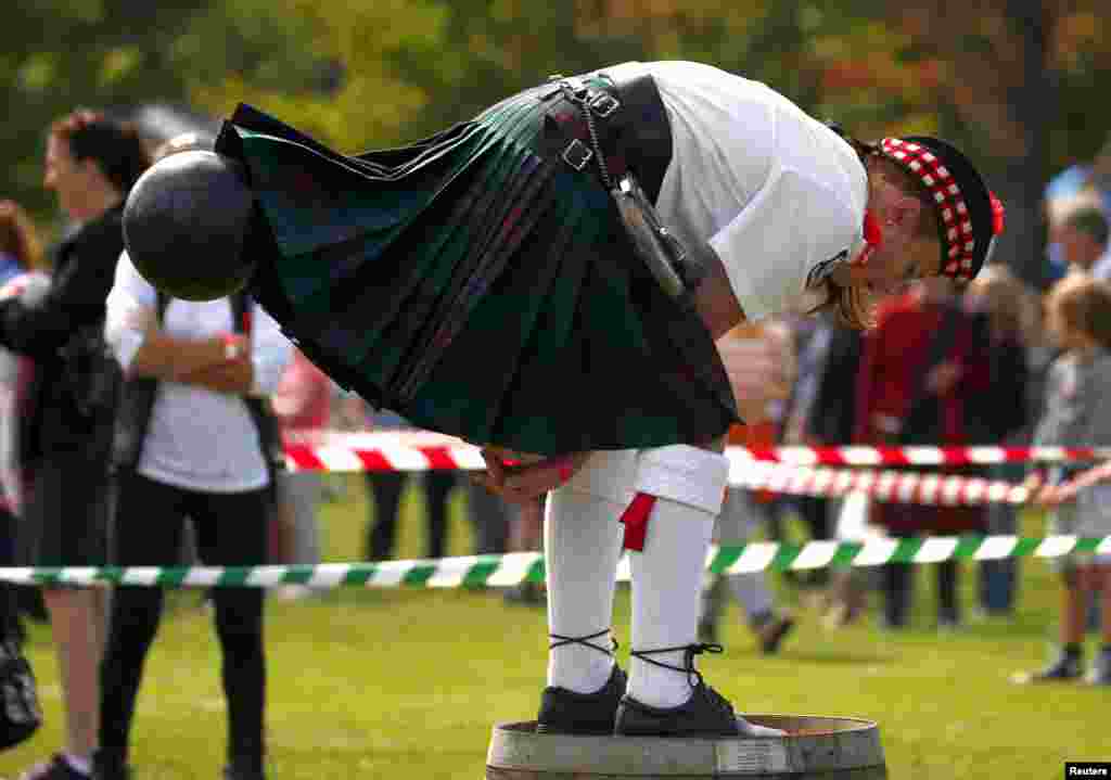 A competitor wearing a kilt and standing on a barrel throws a bowling ball during the &#39;Brigaball&#39; contest at the annual Bundanoon Highland Gathering, showcasing traditional Scottish events, held in the town of Bundanoon, located southwest of Sydney, Australia, April 9, 2016.