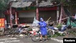 A person pushes a bicycle past damaged buildings, following an earthquake in Luzhou City of southwestern province of Sichuan, China, September 16, 2021. (cnsphoto/via Reuters) 