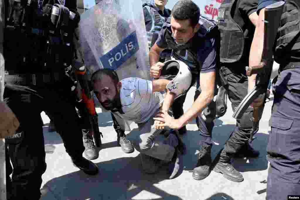 Polisi anti huru hara menahan seorang pengunjuk rasa selam protes menentang skorsing guru-guru atas dugaan kaitan dengan kaum militan Kurdi, di kota sebelah tenggara, Diyarbakir, Turki.
