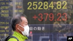 A man walks by an electronic stock board of a securities firm in Tokyo, Nov. 11, 2020. 