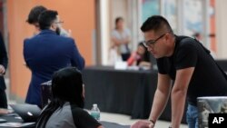 FILE - In this October 2019 photo, a man talks with a representative from GameStop during a job fair at a shopping mall in Miami. On Jan. 10, the US government issues the December jobs report.
