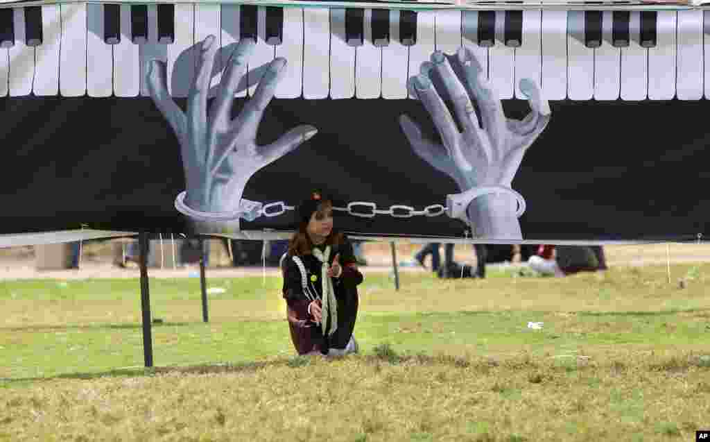 A Palestinian student crawls under a large banner made by Palestinian artists to mark the 40th anniversary of Land Day, in Gaza City.