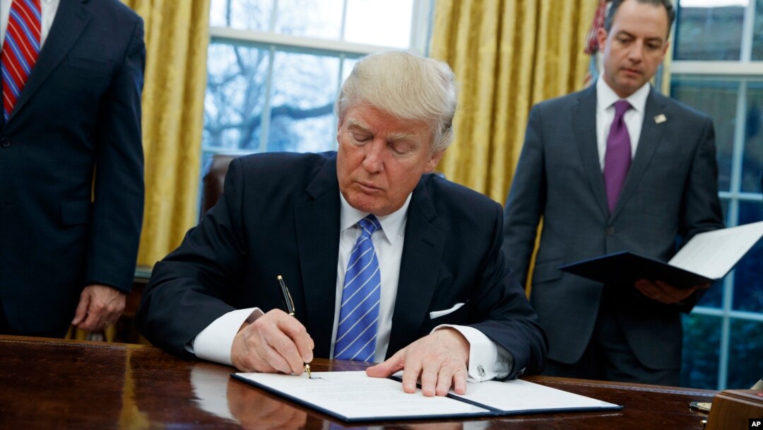 FILE - In this Monday, Jan. 23, 2017, file photo, President Donald Trump signs an executive order to withdraw the U.S. from the 12-nation Trans-Pacific Partnership