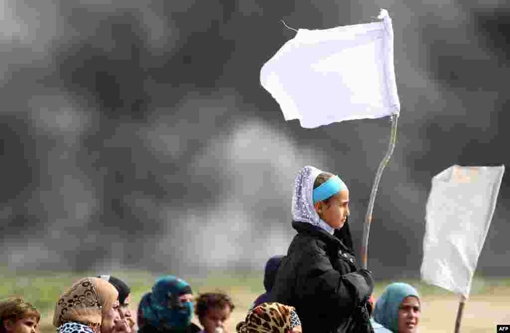 Iraqi girls holding makeshift white flags flee with their families as a military operation by Iraqi security forces, aimed at retaking areas from Islamic State group jihadists continues in the desert west of the city of Samarra.