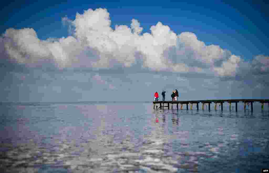 People stand on a bridge at the Jadebusen (Jade Bay) in Dangast on the North Sea coast, northwestern Germany.
