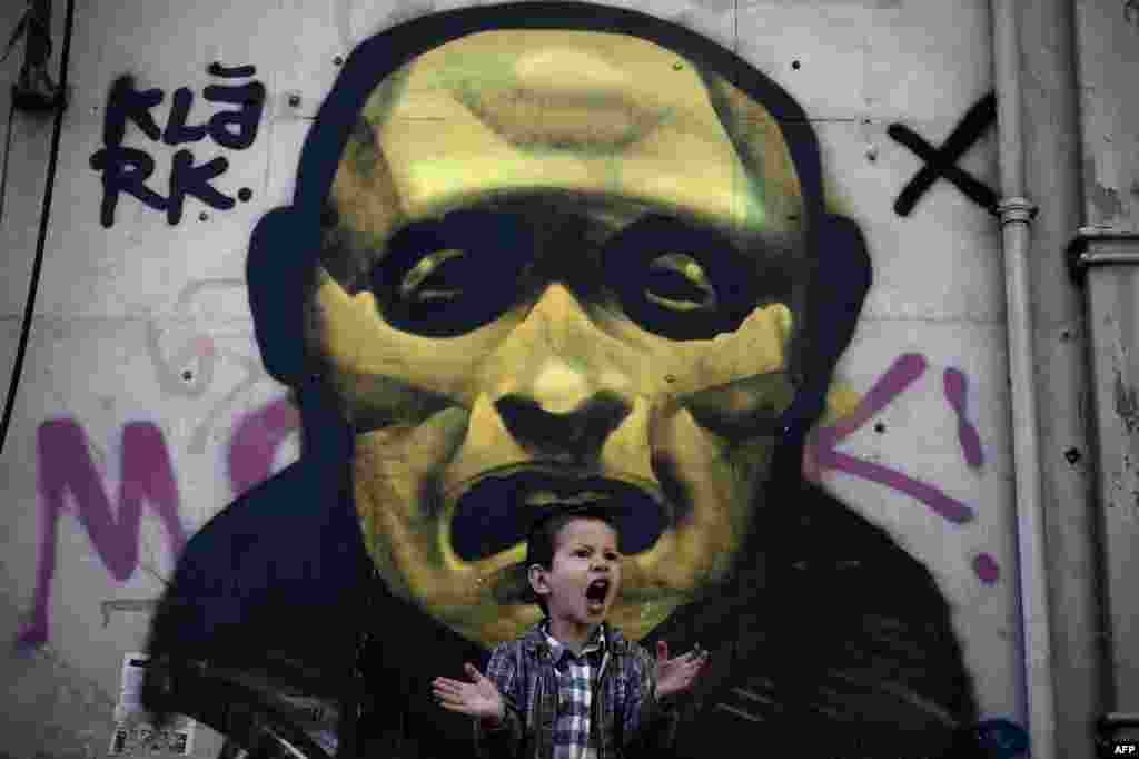 A young boy shouts in front of a street painting in central Athens during a ceremony marking the Greek Independence Day.