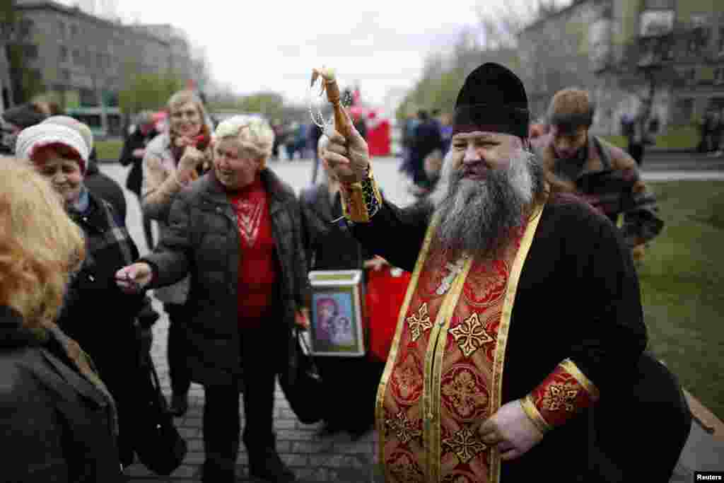 Seorang pendeta Ukraina memercikkan air suci pada jemaat di luar gedung pemerintah daerah pada perayaan Paskah di Donetsk, Ukraina timur.&nbsp;(Reuters/Baz Ratner)