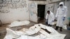 Workers pull bags containing bodies of victims of Saudi-led airstrikes on a Houthi detention center, at a hospital morgue in Dhamar, Yemen, Sept. 2, 2019. 