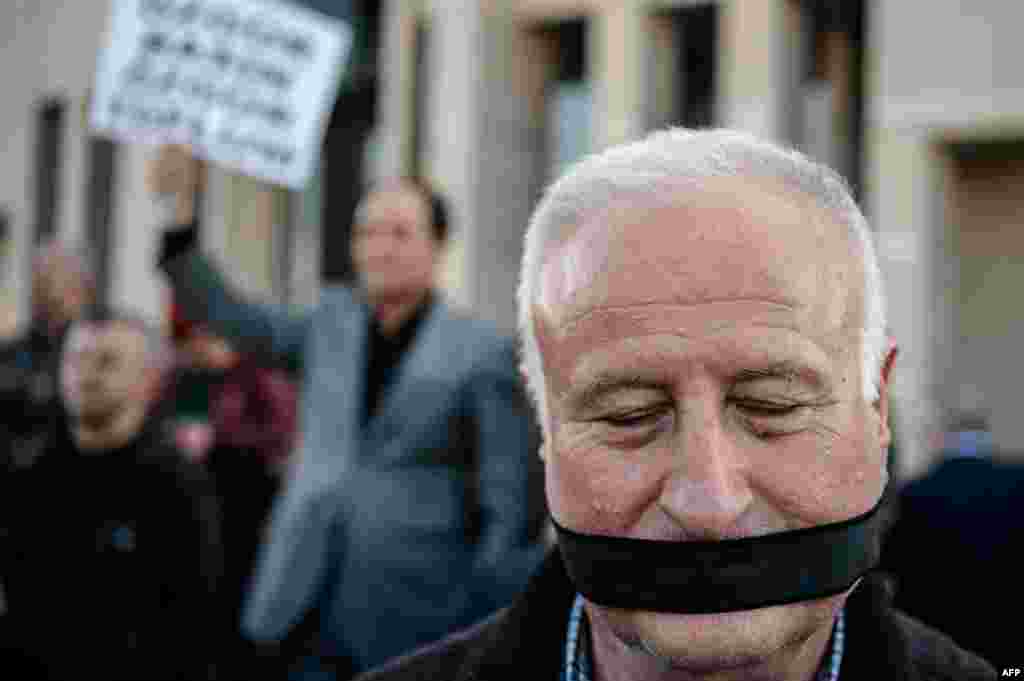 A demonstrator stands outside the Istanbul courthouse, where Turkish opposition Cumhuriyet daily's editor-in-chief Can Dundar and Ankara bureau chief Erdem Gul attend their trial. The two face possible life terms on spying charges over a news report accusing President Erdogan's government of seeking to illicitly deliver arms bound for neighboring Syria.
