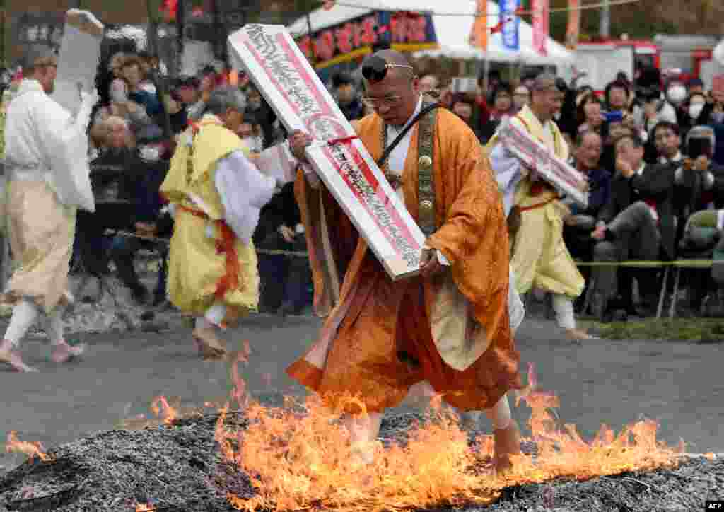Carrying a talisman, a Buddhist ascetic walks barefoot among flames on hot coals during the &quot;Hi-Watari&quot;, or fire walking ceremony, to herald the coming of Spring at the Fudoji temple in Nagatoro town in Saitama prefecture, Japan.