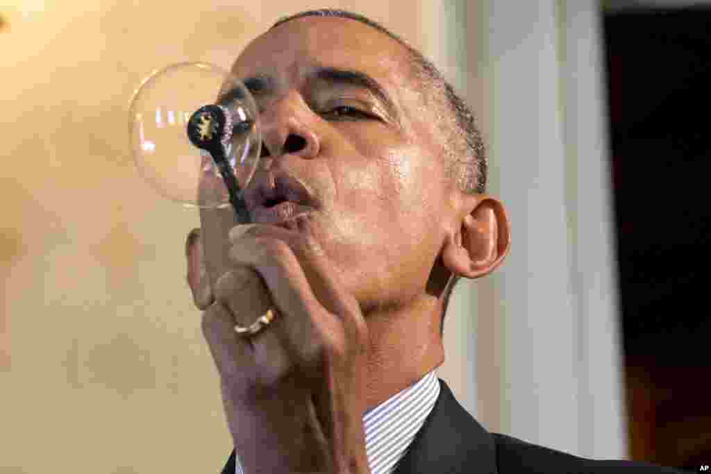 President Barack Obama blows a soap bubble using a 3-D printed bubble wand designed by Jacob Leggette, 9, of Baltimore, Maryland, while touring the 2016 White House Science Fair in Washington, April 13, 2016.