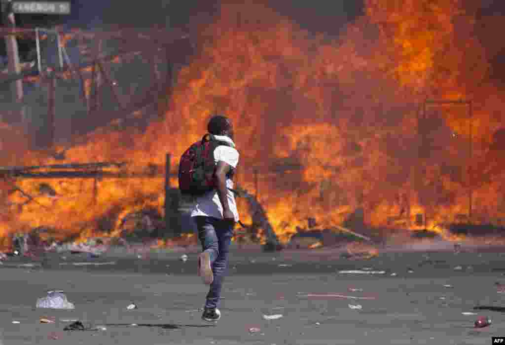 Pendukung oposisi Zimbabwe memasang barikade yang sengaja dibakar ketika mereka bentrok dengan anggota polisi selama terjadinya unjuk rasa menuntuk reformasi pemilihan umum di Harare.