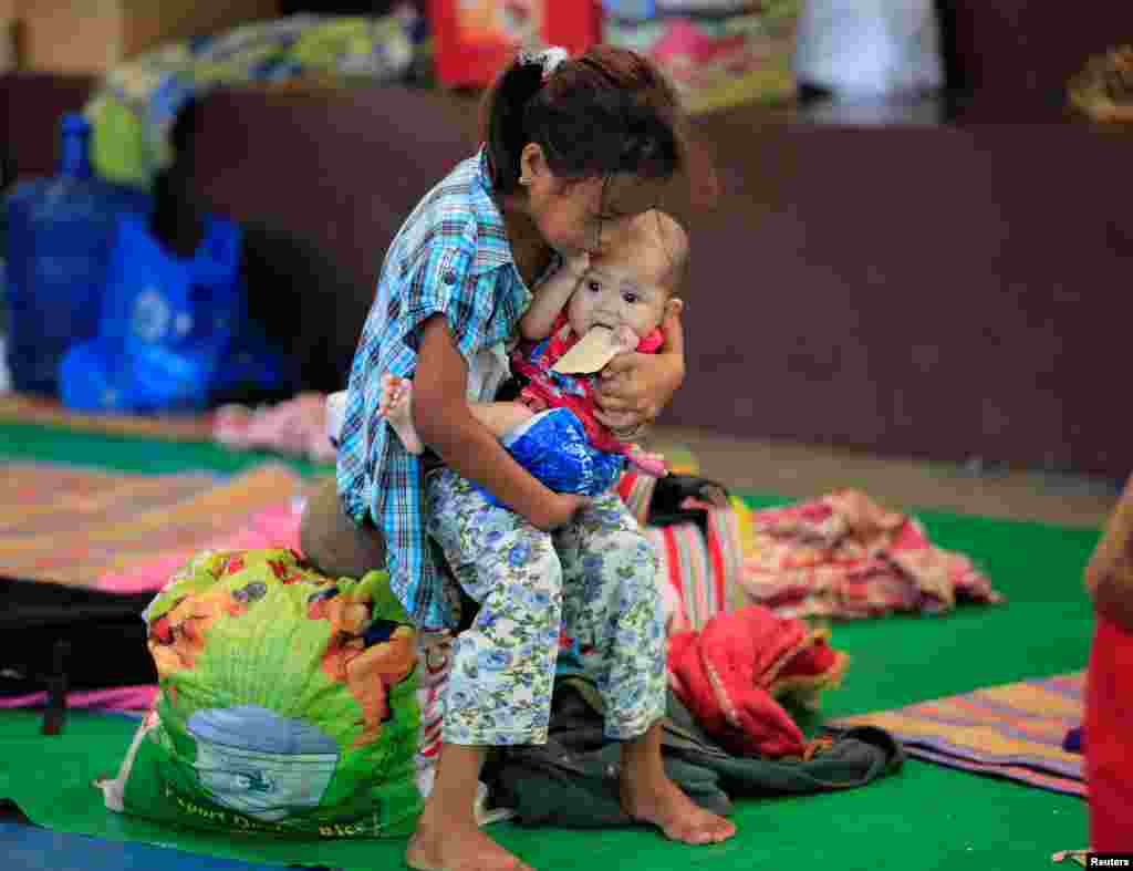 Seorang anak perempuan menggendong adiknya yang masih bayi pada sebuah kamp sementara di Baloi, Lanao Del Norte, bagi warga yang menghindari pertempuran di Mindanao, Filipina.