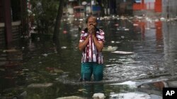 A woman reacts while wading in floodwater in Jakarta, Indonesia, Jan. 4, 2020. Monsoon rains and rising rivers submerged parts of greater Jakarta and caused landslides in Bogor and Depok districts on the city's outskirts as well as in neighboring Lebak.