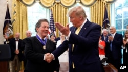 President Donald Trump shakes hands with economist Arthur Laffer after awarding him the Presidential Medal of Freedom, June 19, 2019, in the Oval Office of the White House in Washington. 