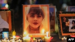 FILE - Candles and pictures of Mahsa Amini, who died in custody of Iran's morality police, are shown during a vigil for Amini, in Los Angeles, Sept. 29, 2022. 