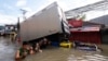 People wade through a flooded road brought about by Tropical Storm Trami in Naga, Camarines Sur, on Oct. 25, 2024. Philippine rescue workers battled floodwaters to reach residents still trapped on the roofs of their homes as Trami moved out to sea. Eleven people died in Naga.