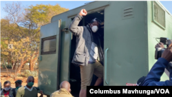 Le journaliste Hopewell Chin'ono lève le poing devant ses collègues, sa famille et ses amis alors qu'il monte dans un véhicule de prison, le 23 juillet 2020, devant le tribunal de Harare. (Photo: Columbus Mavhunga/VOA)