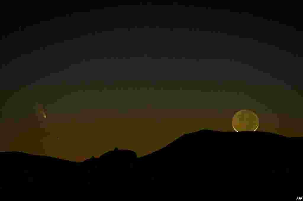 Sebuat komet PanSTARRS (kiri) terlihat pada malam hari di sebelah bulan, melalui sebuah teleskop di dekat Magdalena, negara bagian New Mexico, Amerika Serikat.