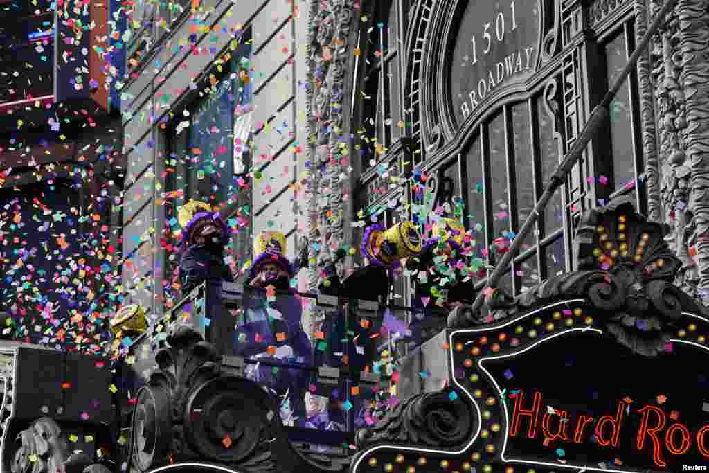 People stand on a balcony and &#39;flight test&#39; some confetti ahead of the New Year&#39;s celebration in Times Square during the COVID-19 pandemic in the Manhattan borough of New York City.