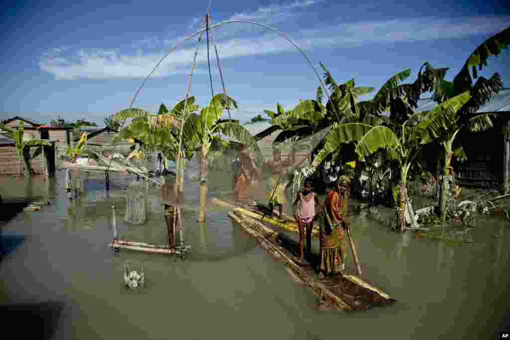 Satu keluarga di distrik Morigaon, Gauhati, negara bagian Assam, India menggunakan rakit dari batang pisang untuk mengungsi dari kawasan banjir.