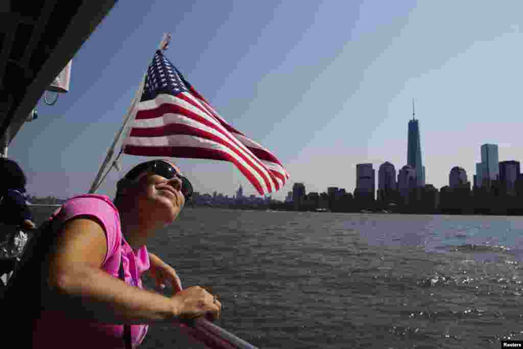 Seorang perempuan naik feri dan menikmati pemandangan di Kota New York. 