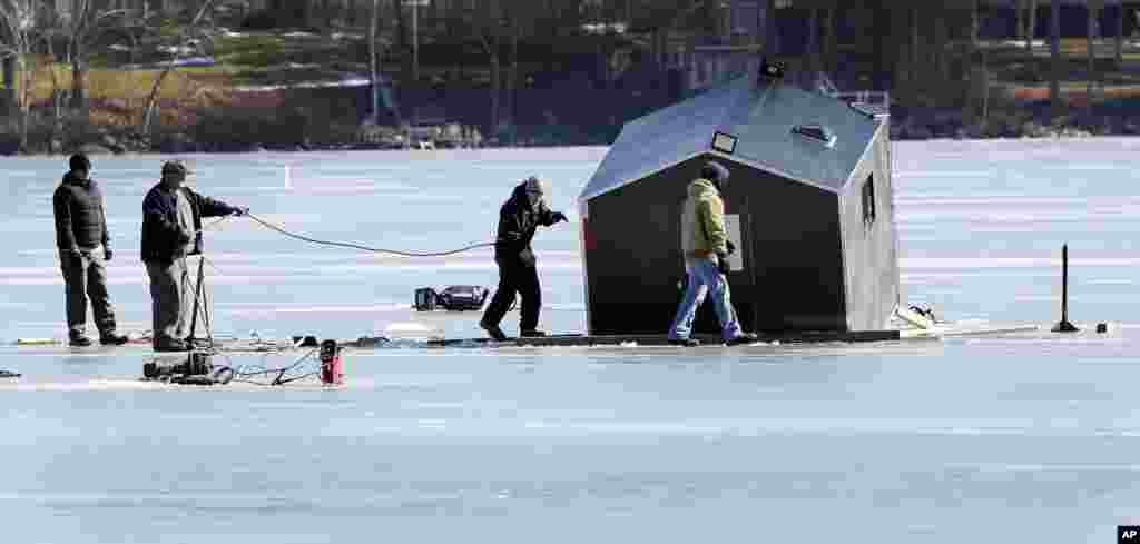 A crew from Gulbicki&#39;s towing service works to extract a bob house that broke through the ice on Lake Winnipesaukee in Meredith, New Hampshire, USA. The small shack is used by ice fisherman and broke through the ice over the weekend.