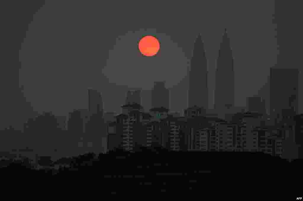 A general view shows Malaysia's landmark Petronas Twin Towers (2nd R) and Kuala Lumpur Tower (L) as a layer of haze covers the city during sunset.