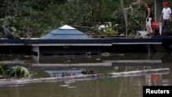 在波多黎各的瓜亚塔卡水坝附近，洪水淹没房屋，人们站在房顶上（2017年9月23日）