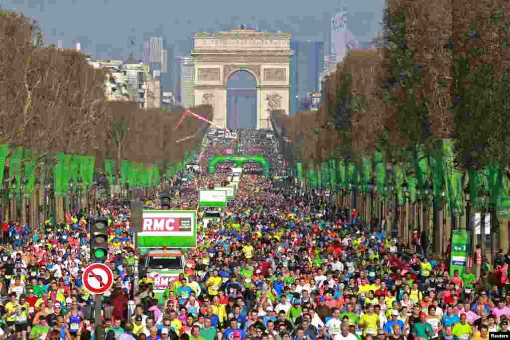 Competitors run down the Champs Elysees below the Arc de Triomphe at the start of the 40th Paris Marathon in France.