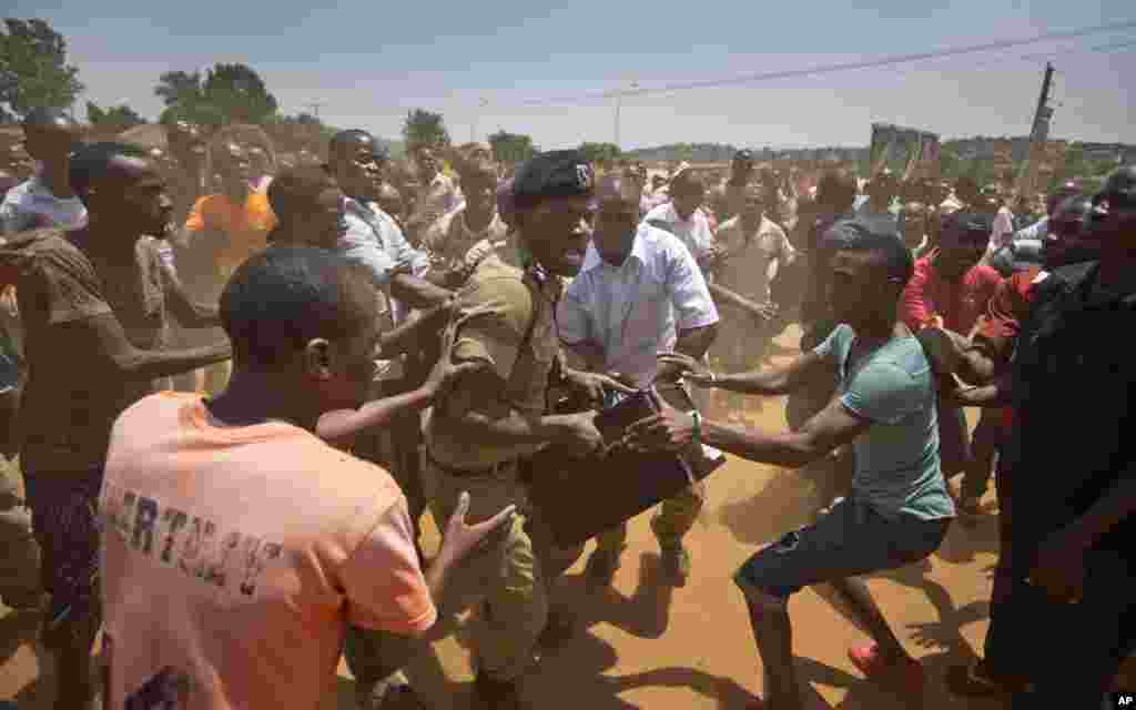 A Ugandan policeman struggles to keep his hold of a box containing voting material, as excited voters surround him after waiting over seven hours without being able to vote, at a polling station in Ggaba, on the outskirts of Kampala.