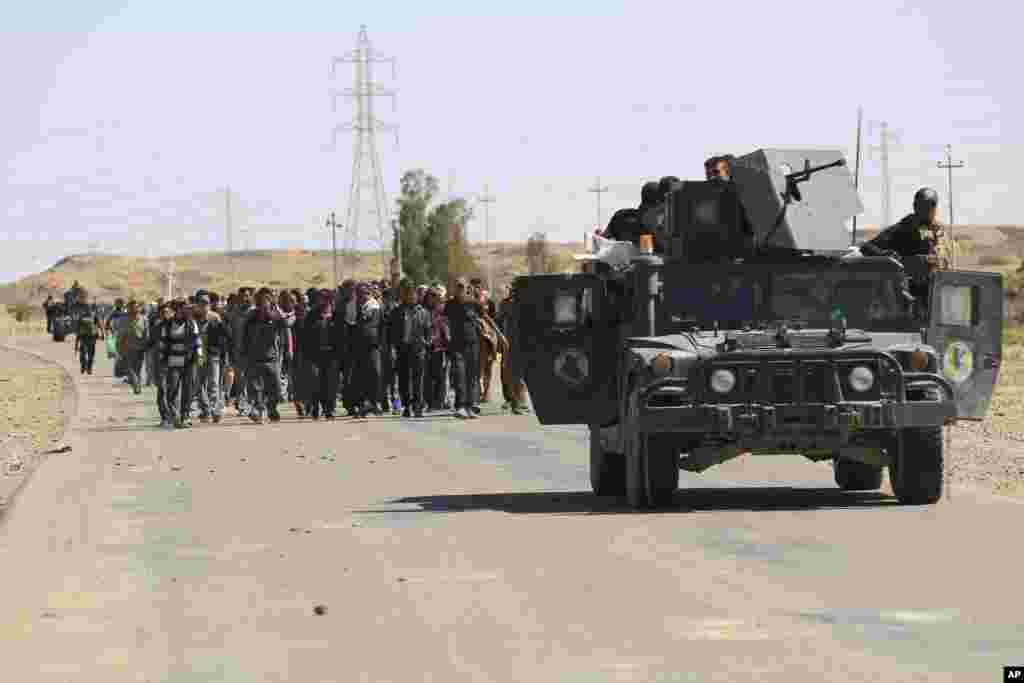 Counterterrorism forces escort people fleeing their homes during clashes between Iraqi security forces and the Islamic State group in Hit, 85 miles (140 kilometers) west of Baghdad, Iraq.