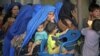 FILE - An Afghan woman and her children wait to be repatriated to Afghanistan from a United Nations Humanitarian Commission for Refugees registration center in Peshawar, Pakistan, Jun 20, 2010.