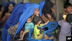 FILE - An Afghan woman and her children wait to be repatriated to Afghanistan from a United Nations Humanitarian Commission for Refugees registration center in Peshawar, Pakistan, Jun 20, 2010.